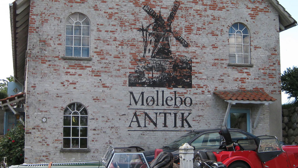 The facade of Møllebo Antik with the shop's logo on the wall