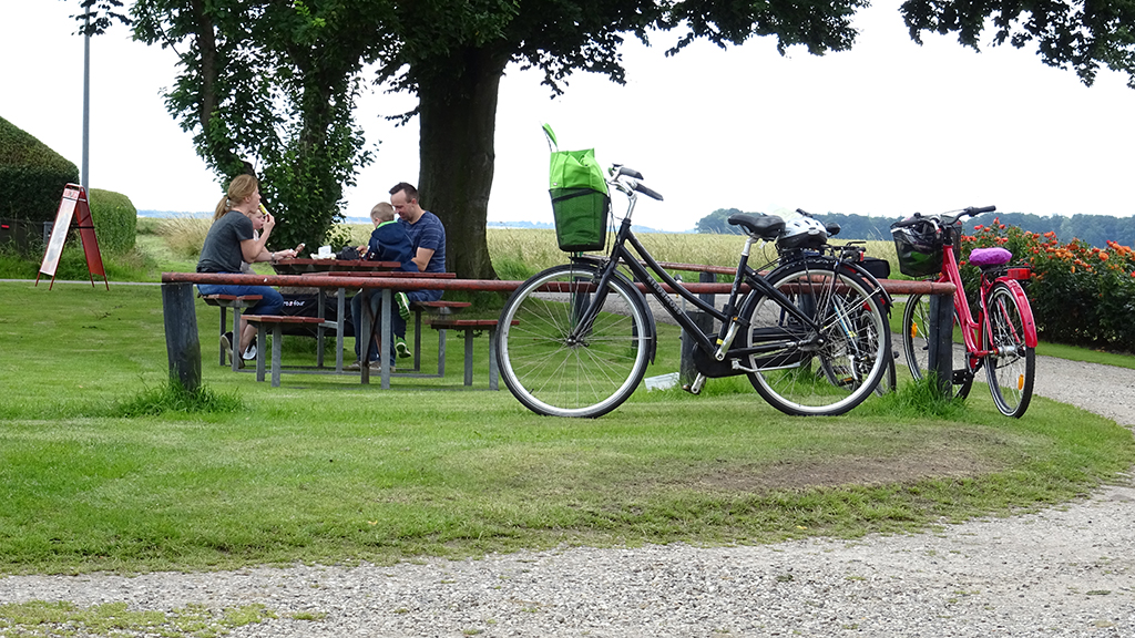 A family on a bike ride takes an ice cream break at a picnic table