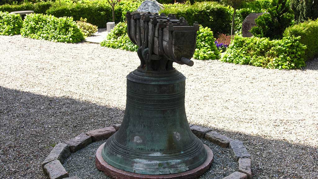 The church bell of Saksild Church outside the church