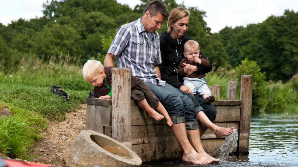 Family sitting by the water at Mossø