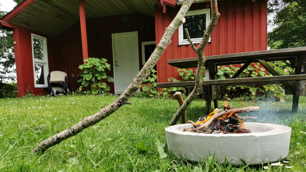 Red annex with a terrace, fire pit, and a bench at Holmely
