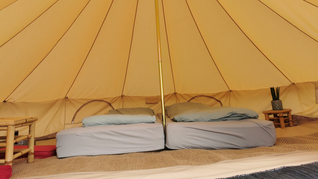 Glamping tent viewed from the inside with a made bed at Holmely
