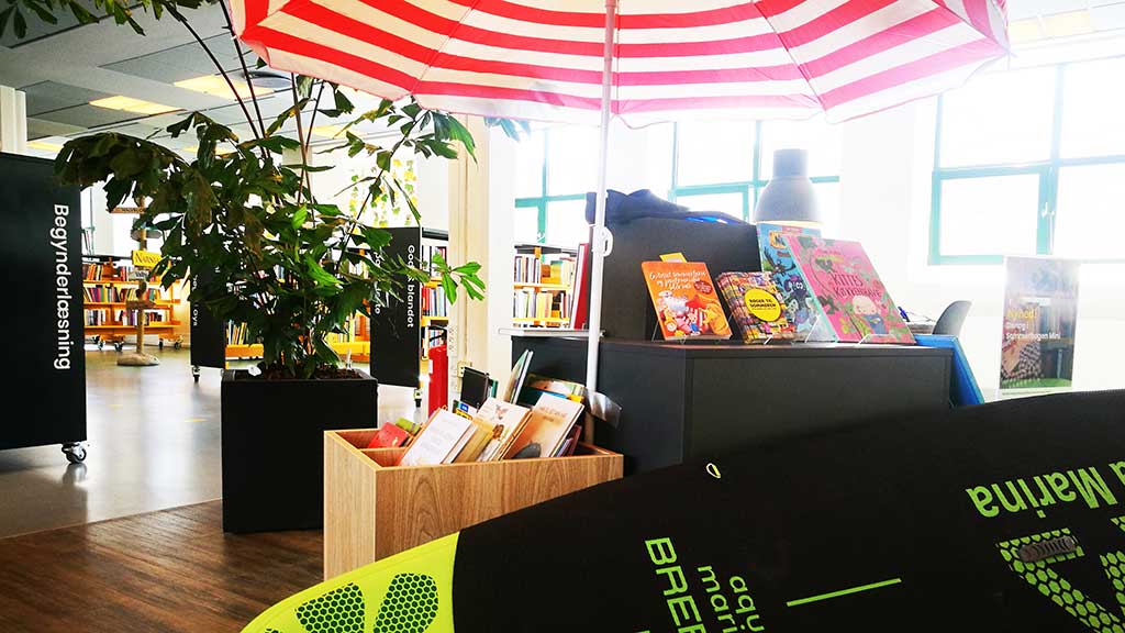 Books are lying under a parasol along with a SUP board at Horsens Library