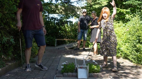 Lille pige spiller minigolf med sin familie