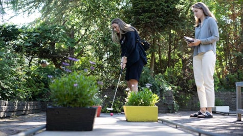 Kvinde slår til golfbolden hos Juelsminde Minigolf