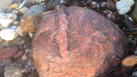 rød sten ligger på en strand