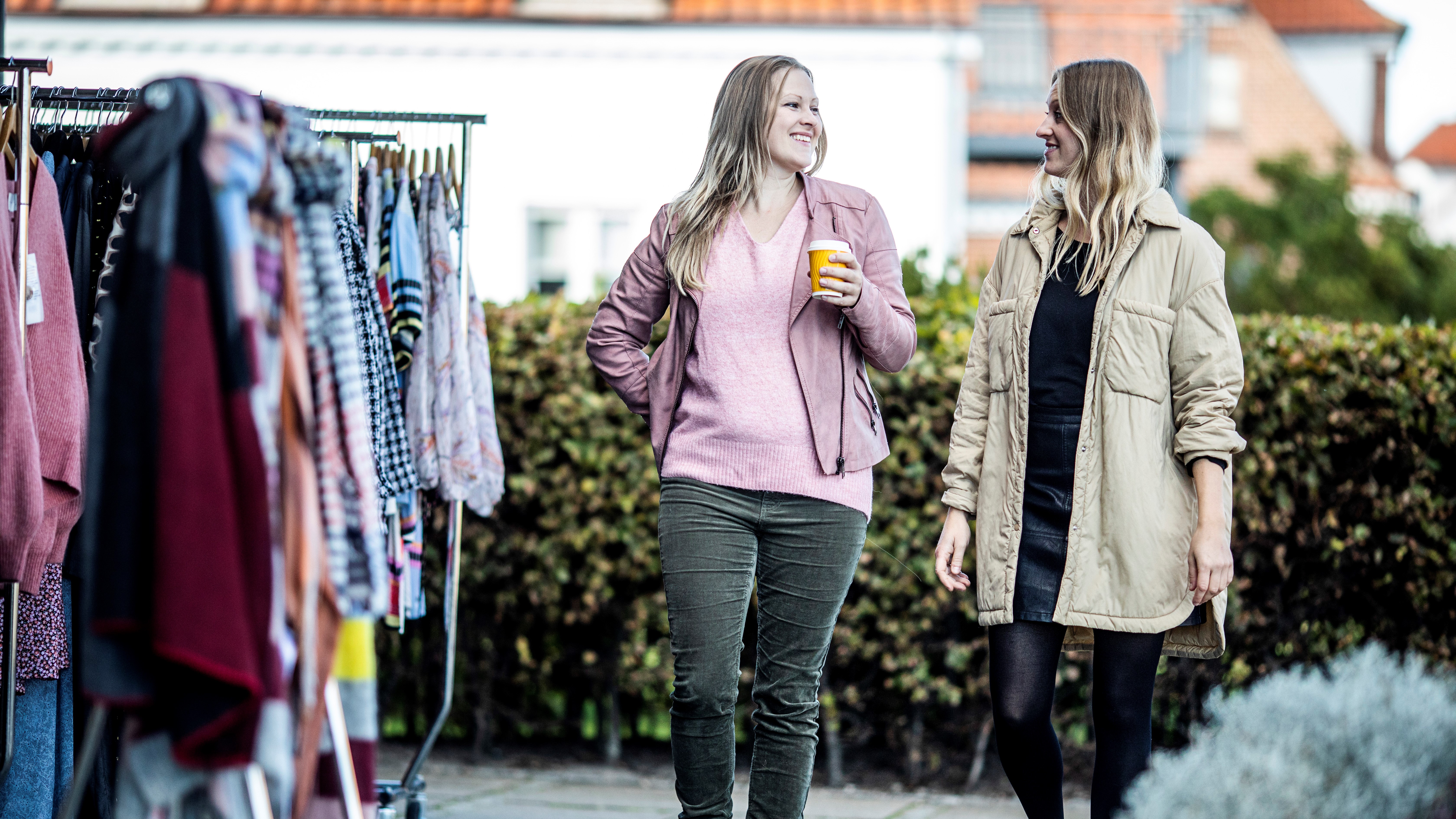Two friends walk past clothing racks with fashion outside Lykke & Lykke in Juelsminde