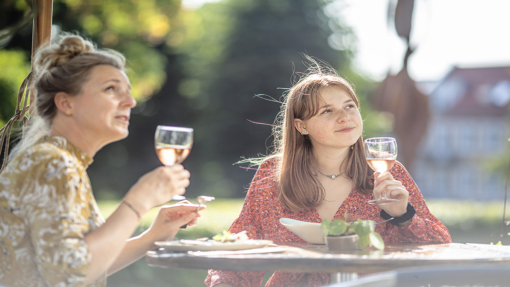 Two women toast at an outdoor table at Café Ella in Horsens Art Museum