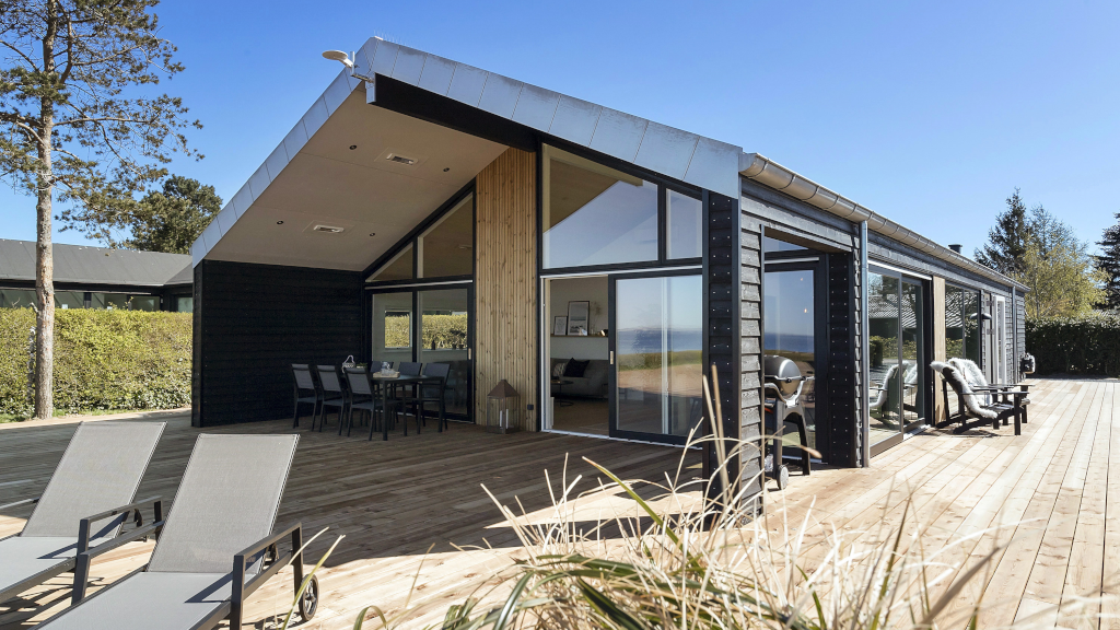 The facade of a modern Danish holiday home with a large wooden terrace