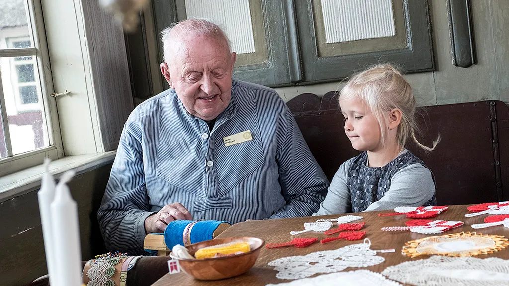 Ældre mand og lille pige laver knipler på Glud Museum