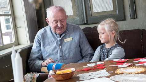 Ældre mand og lille pige laver knipler på Glud Museum