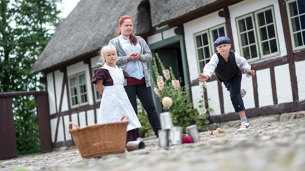 dreng og piger har historisk tøj på og leger på Gludmuseum