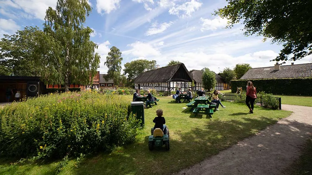 Besøgende sidder ved bord bænkesæt på græsplænen ved Gludmuseum
