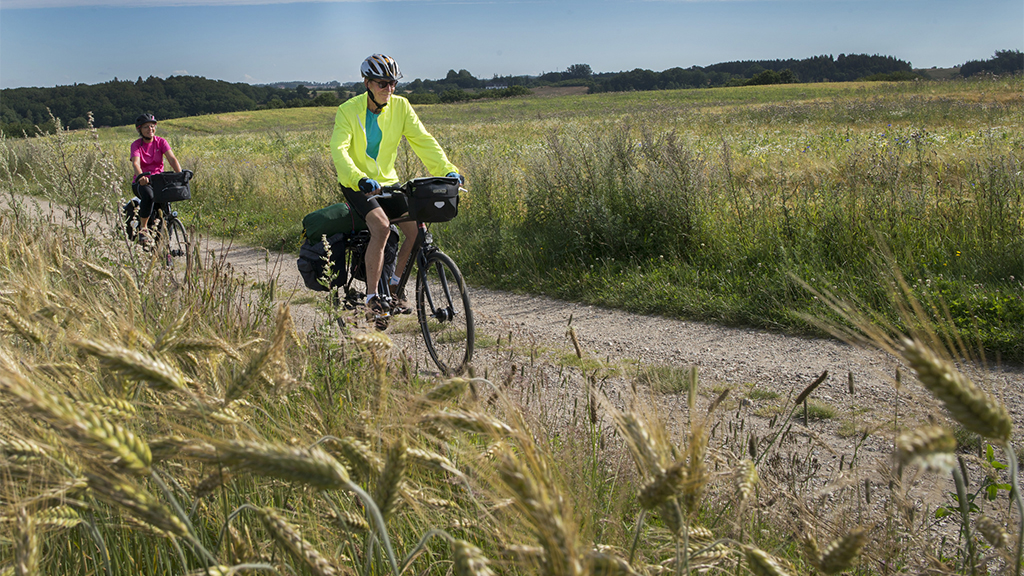 A couple cycling on the Ancient Road between fields