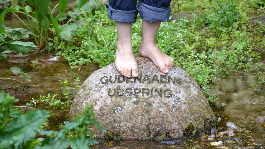 A child stands on the rock at the source of the Gudenå River