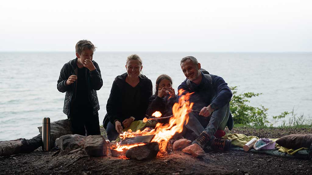 A family is enjoying a campfire on the shelter site by the coast