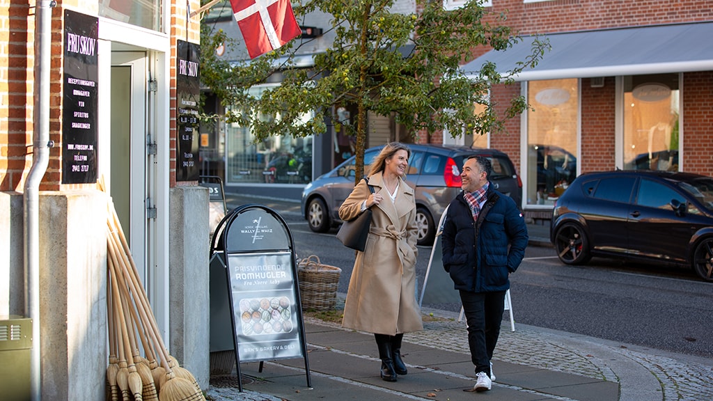 Et par bestående af en mand og dame går igennem Brædstrup by i Destination Kystlandet på shoppetur