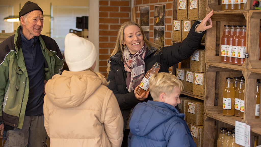 A family is looking at apple juice on the shelves at Karensminde Frugtplantage