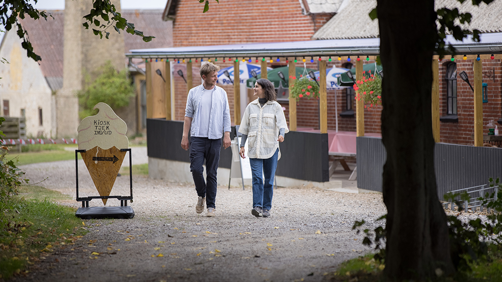 A couple is walking by the outdoor dining area at Endelave Campsite