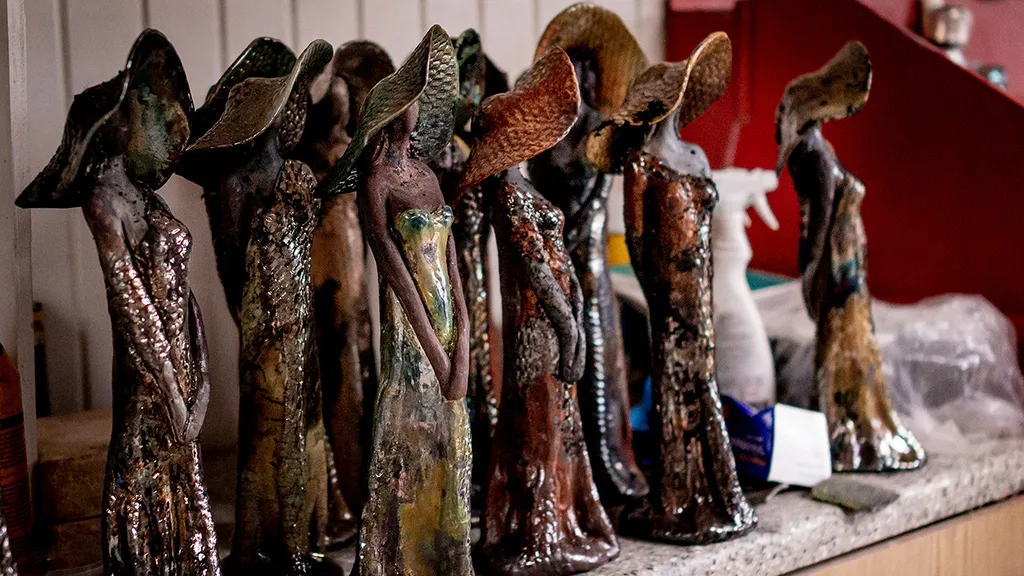 A collection of ceramic figures in brown and burnt tones, depicting women with hats