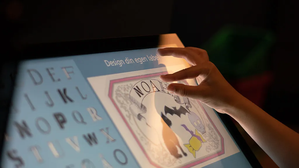 Barnearm indover en skærm på en labelmaker på industrimuseet i Horsens