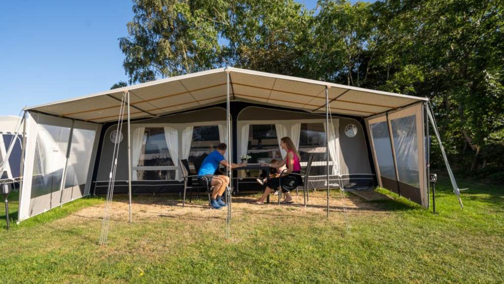 A family enjoying themselves in a large awning tent on the site at Horsens City Camping