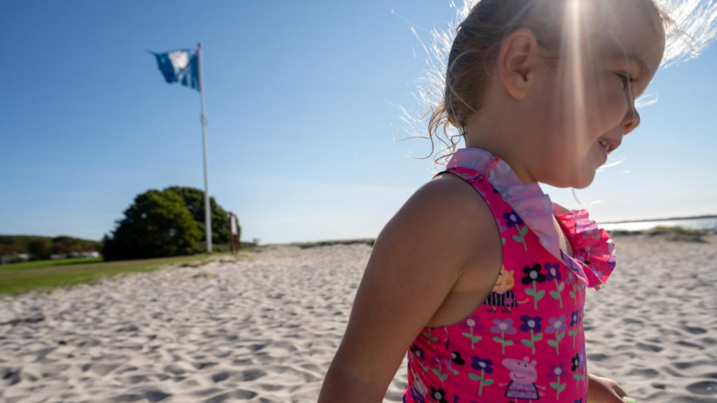 A girl playing in the sand by the Blue Flag at Husodde Beach