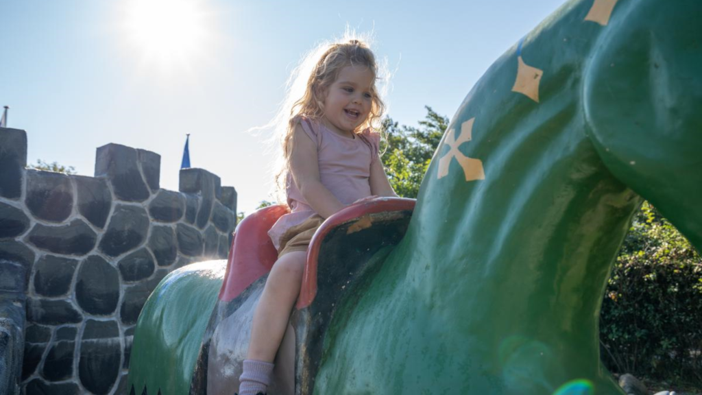 A girl playing on a horse sculpture by the mini-golf course at Horsens City Camping