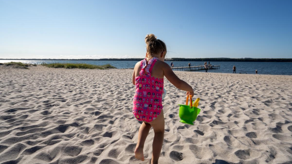A girl playing in the sand on a summer day at Husodde Beach