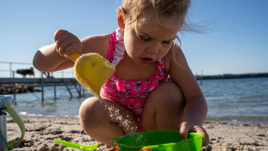 A girl playing at the water's edge on Husodde Beach on a summer day