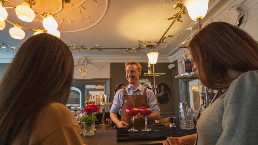 A waiter serves cocktails in the wine bar at Jørgensens Hotel