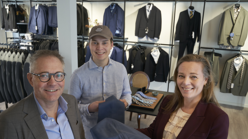 Das Personal steht vor einer Auswahl an Anzügen und Blazern bei Velklædt in Odder.