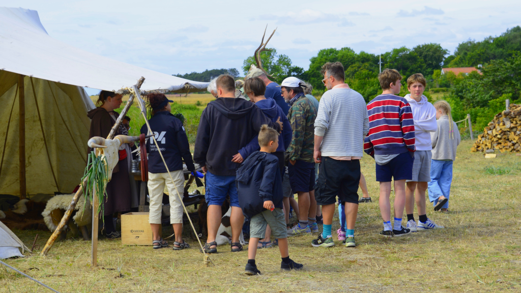A group of people is looking at goods in a Viking tent.
