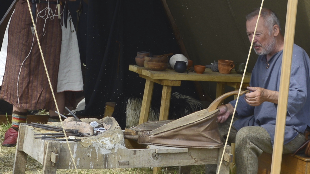 A man is using Viking tools at the Tunø Viking Camp.