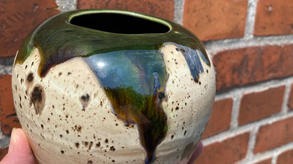 Stoneware vase photographed in front of a red brick wall