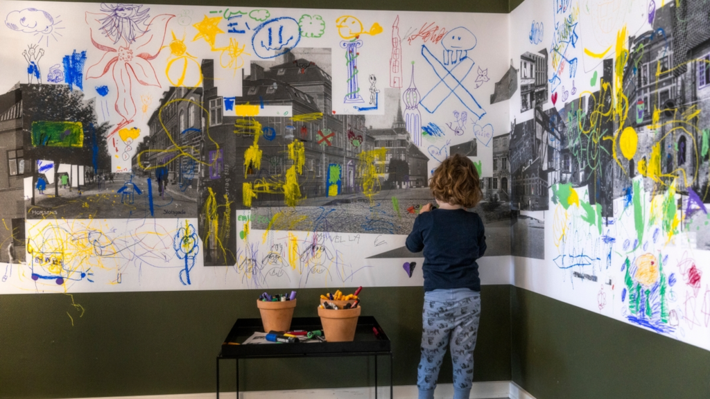 A girl is drawing on pictures of Horsens for the Makværk Festival