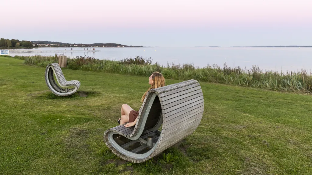 Kvinde nyder udsigten over Horsens Fjord i stol ved Langelinie i Horsens