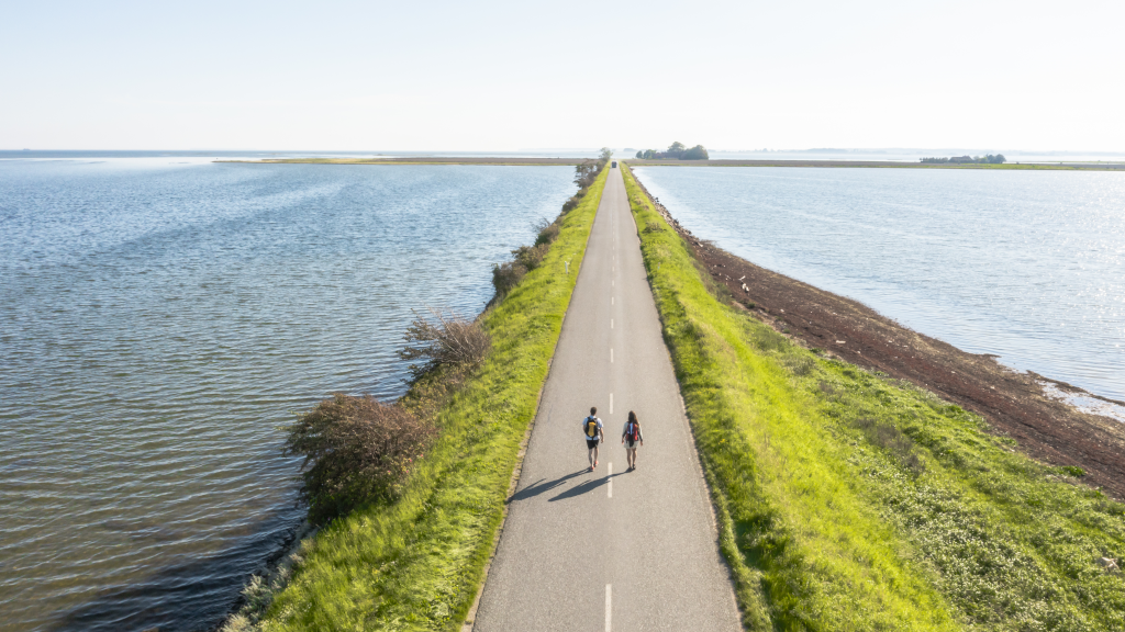 Drone photo of a couple hiking on the dike to Alrø