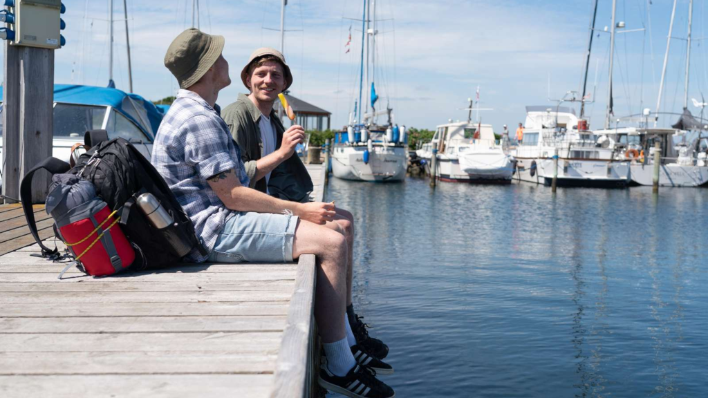 Two men sitting on the pier at Snaptun Harbor, eating ice cream