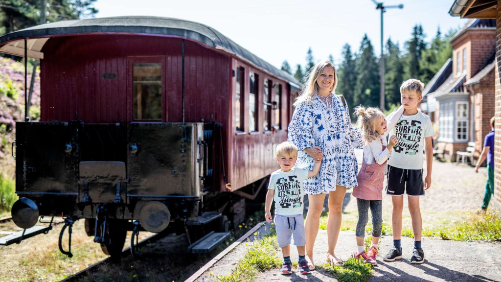 Mother and two children standing in front of a train carriage at Vrads Station