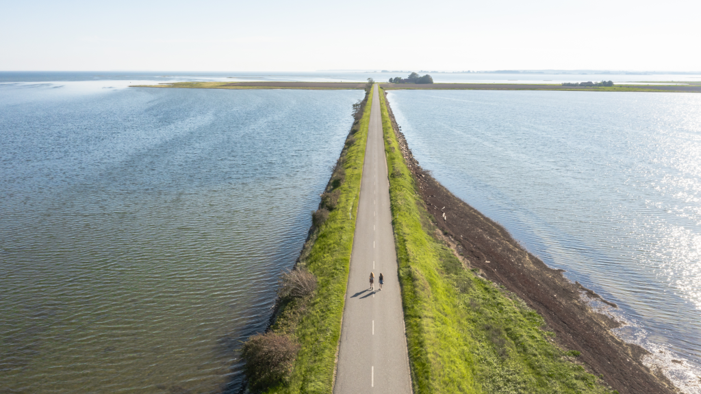 Two women walking on the Alrø causeway on the Fjordmino