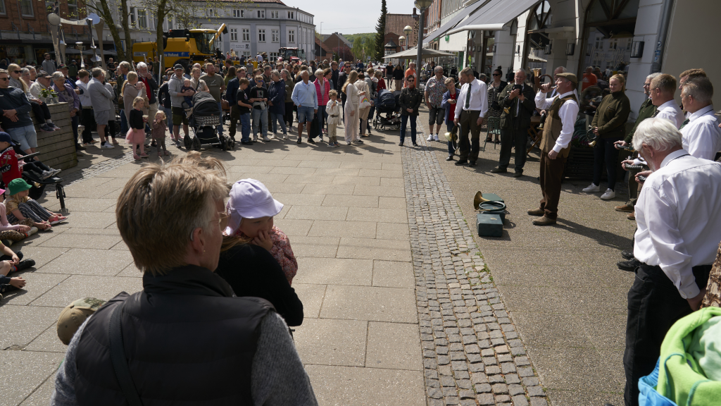 Mand spiller musik på gågaden i Odder omgivet af en menneskemængde