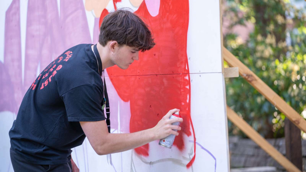 A boy painting graffiti on a canvas at the Horsens Holder festival