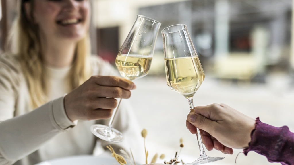 Two women clink glasses with white wine