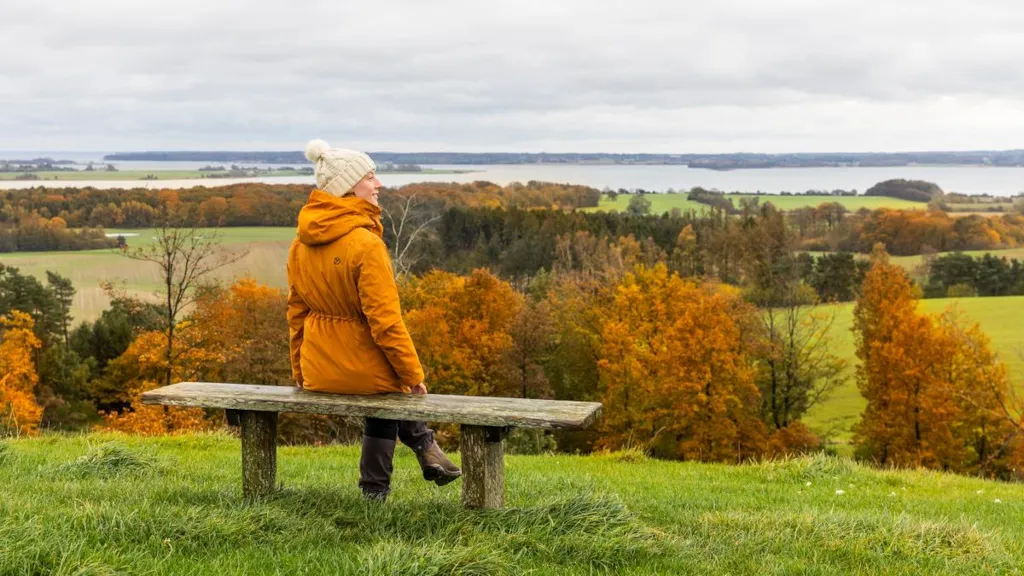 Kvinde sidder på en bænk og nyder udsigten over Horsens Fjord i Trustrup Udsigtshøje
