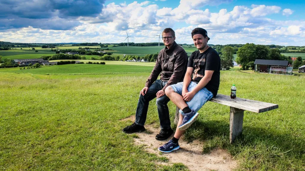 To drenge sidder på en bænk i Trustrup Udsigtshøje med udsigt over marker og vindmøller