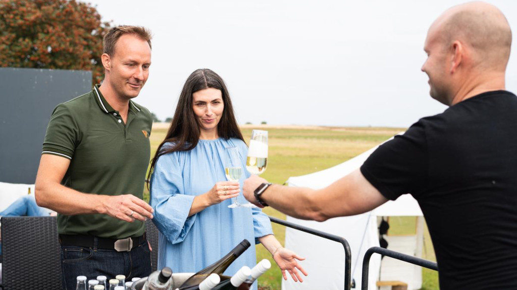 Waiter serving champagne to a couple on the terrace at Mejeriet Tunø