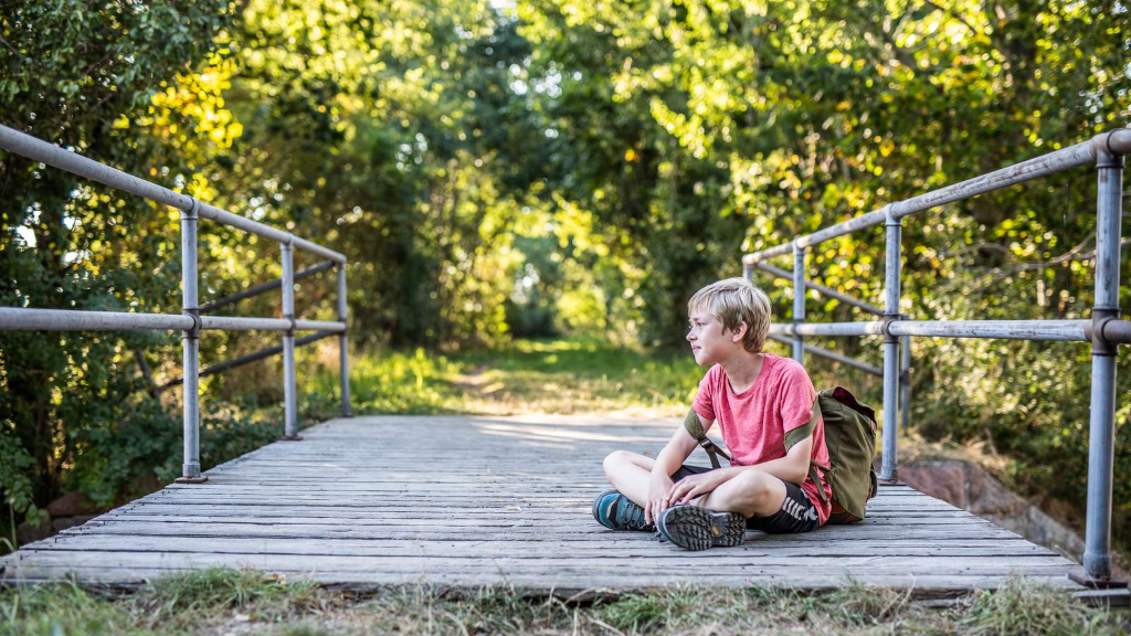 A boy sitting on a bridge in Stensballe Forest
