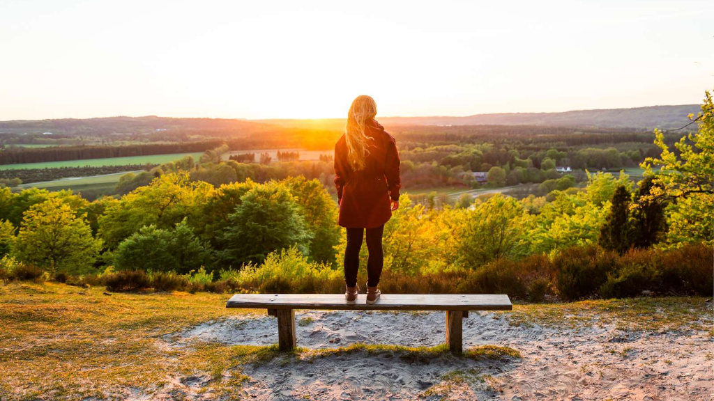 Woman standing on a bench on a hilltop