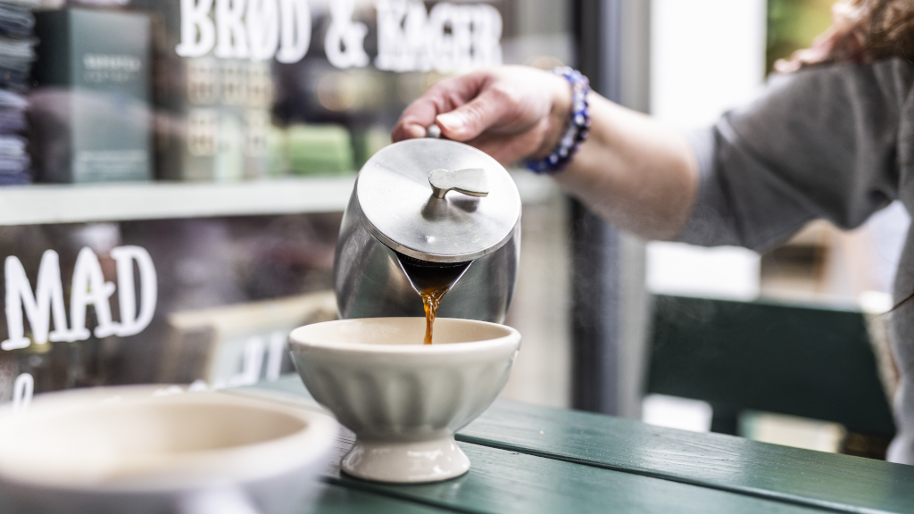 Eine Frau gießt Kaffee in eine Tasse bei Spisekammeret in Horsens